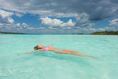 Girl floating in the criystal clear of mexican caribbean