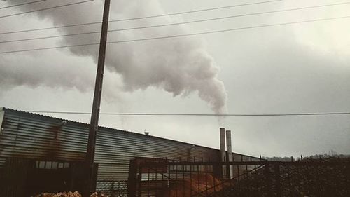 Low angle view of power lines against cloudy sky