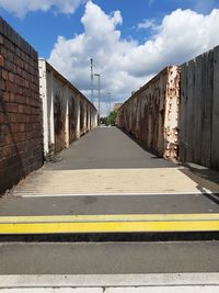 Road amidst buildings against cloudy sky