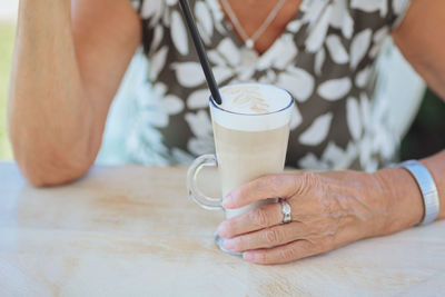 Cropped photo of senior woman holding cup of coffee outdoors