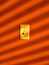 Close-up of switch on orange wall