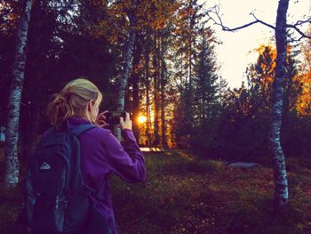 Rear view of woman standing amidst trees in forest