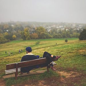 Men sitting on agricultural field against sky