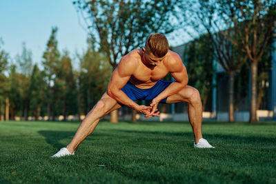 Full length of man sitting on grass against trees