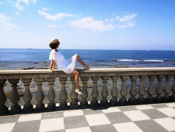 Woman standing by sea against sky