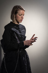 Woman using phone against gray background
