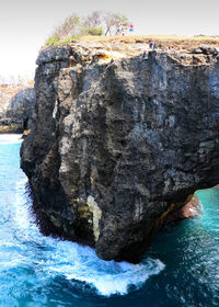 Rock formation on sea shore against sky