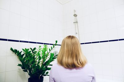 Rear view of woman against wall in bathroom