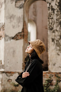 Portrait of young woman standing against wall