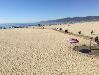 Panoramic view of people on beach against clear blue sky