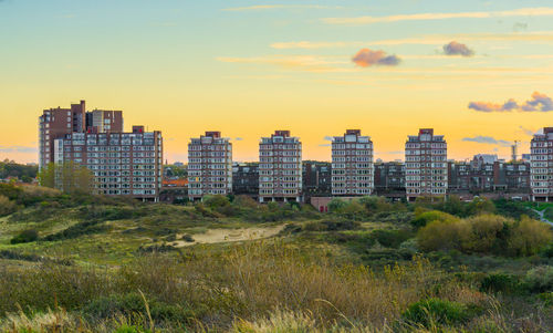 Buildings in city against sky during sunset