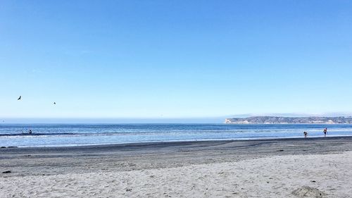 Scenic view of beach against clear blue sky