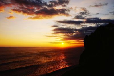 Scenic view of sea against dramatic sky during sunset