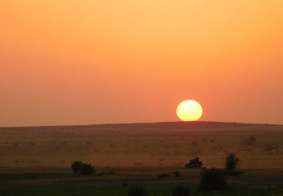 Scenic view of field against orange sky