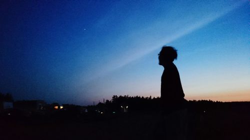 Silhouette people standing on landscape at sunset