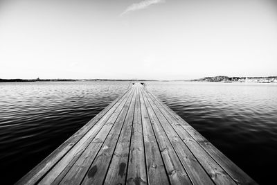 Wood paneled jetty at calm sea against clear sky