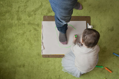 High angle view of daughter drawing with her father foot on paper at home