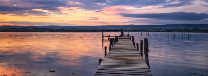 Pier over lake against sky during sunset