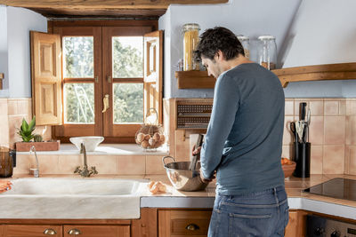 Middle aged man mixing ingredients in dough to cook homemade pastry