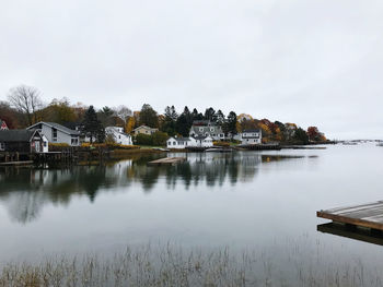 Buildings by lake against sky