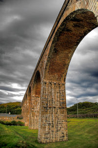 Old ruin on field against storm clouds