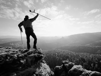 Rear view of man standing on mountain against sky