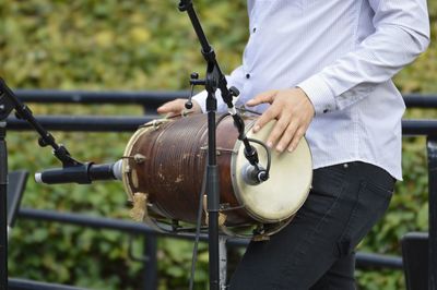 Midsection of man playing drum during event