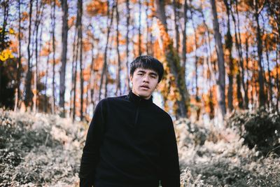 Portrait of young man standing in forest