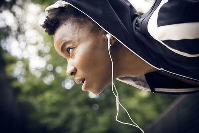 Sportswoman listening music on headphones while exercising at park