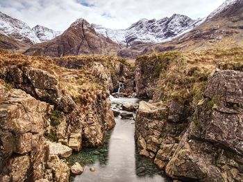 Water flowing through rocks against sky