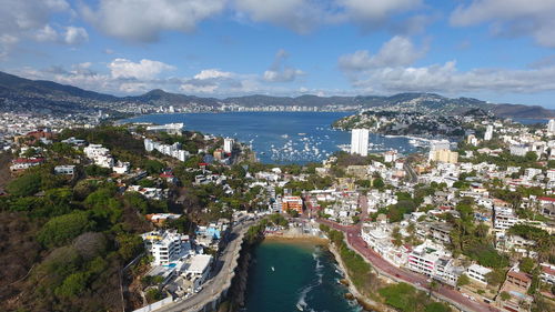 High angle view of city by sea against sky