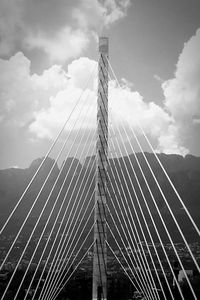 Low angle view of suspension bridge against cloudy sky