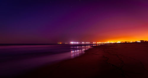 Illuminated beach against sky at night