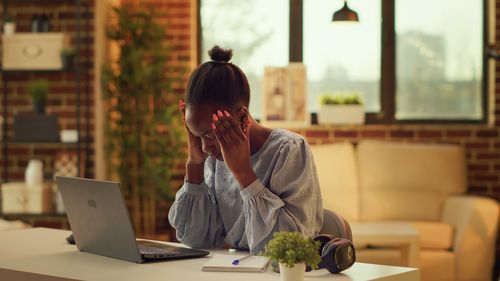 Young woman using laptop while sitting on chair at home