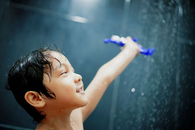 Cute boy having shower in bathroom