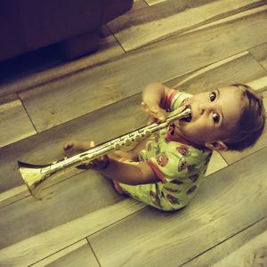 Portrait of cute girl playing on hardwood floor at home