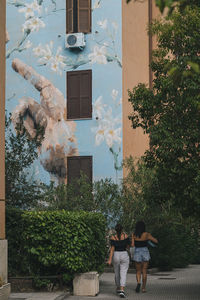 Rear view of couple walking against building