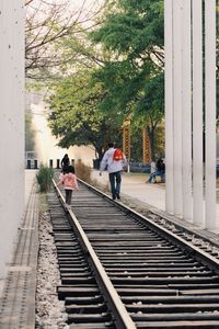 Rear view of father with daughter walking on railroad track