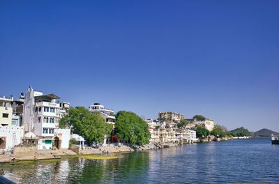 Buildings at waterfront against blue sky