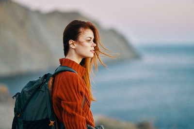 Young woman looking away while standing in sea