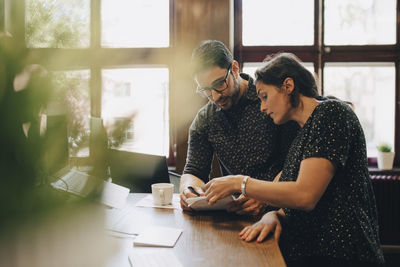 Multi-ethnic business people discussing over documents at desk in office