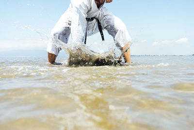 Karate man punches the water with his fist