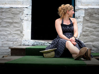 Woman sitting on steps against house