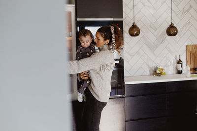 Mother carry toddler son in kitchen