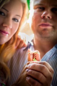 Close-up of couple with anthropomorphic face and rings in thumbs