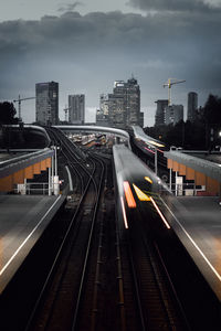 Light trails on railroad track against cloudy sky