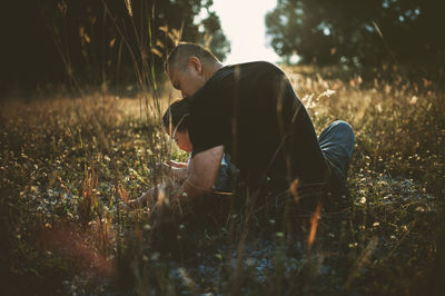 Rear view of father with son sitting on grassy field
