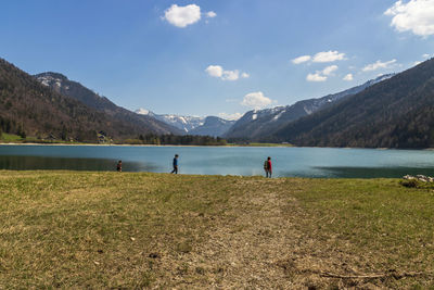People at lake against mountains 