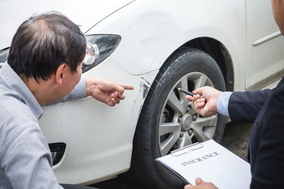 Man showing scratched car to insurance agent with form