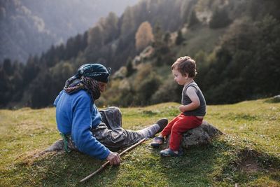 Father and son sitting on mountain